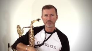 Nigel McGill holding his saxophone while sitting